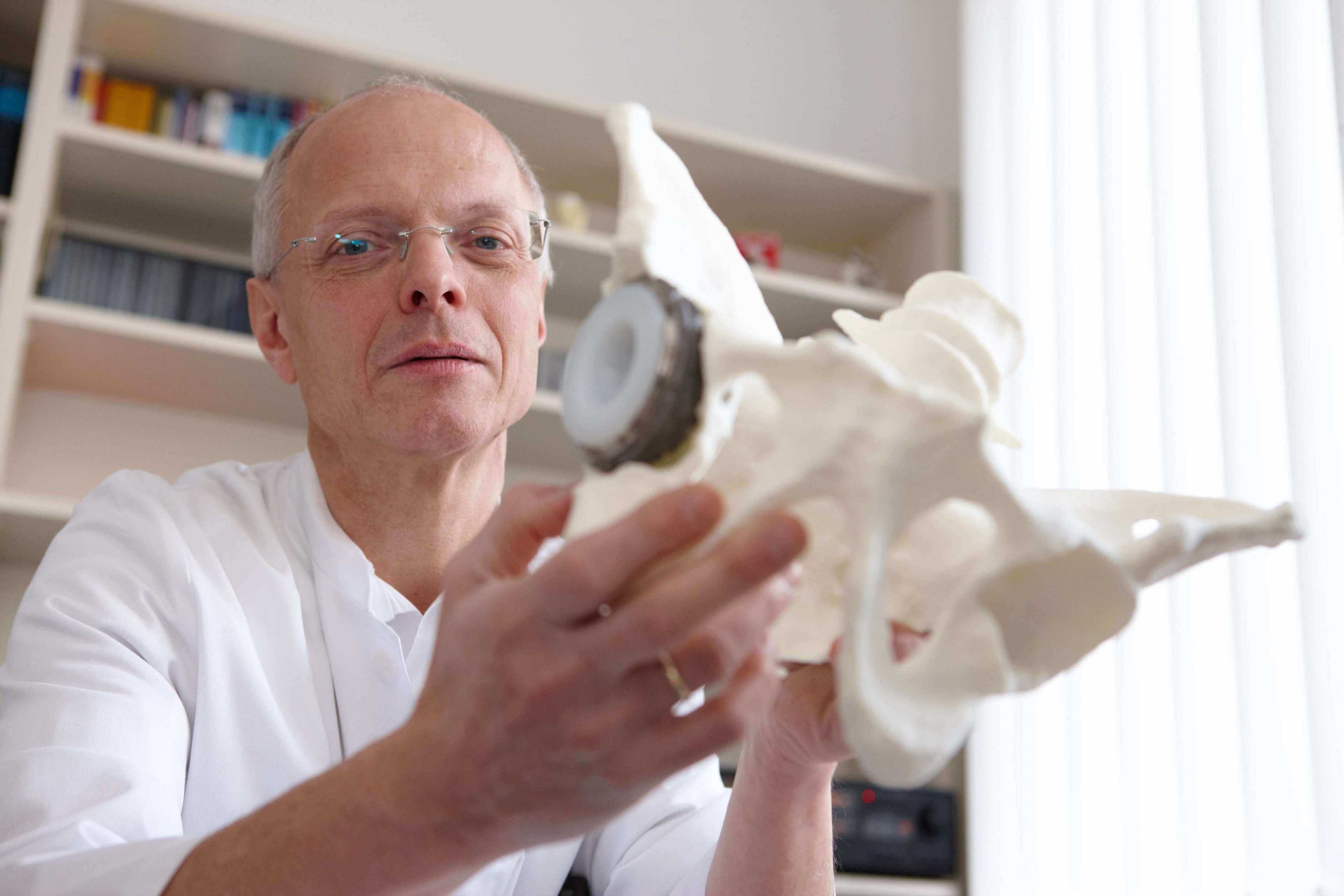 Dr. Peter-Michael Hax mit einer Knochennachbildung in der Hand